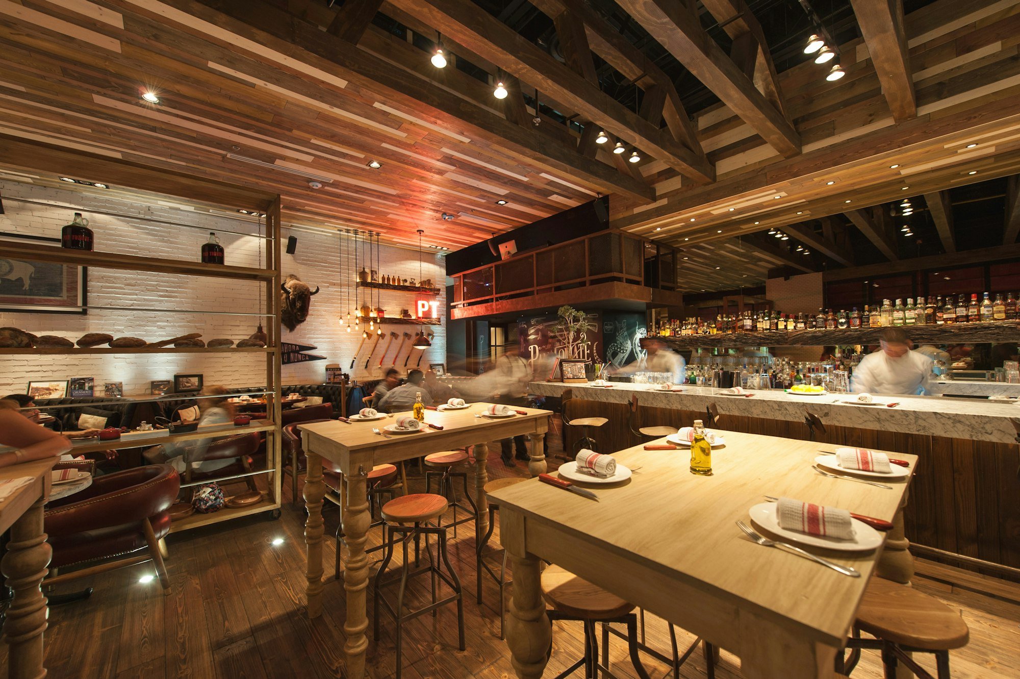 La salle du Bistrot Fenouil, ses tables en bois et la cuisine ouverte